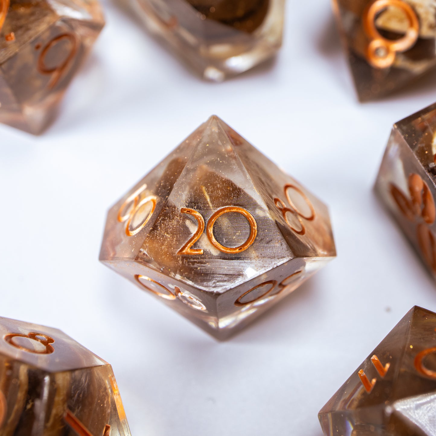 A close-up of a ten sided die at the heart of its kin, the rest of the coffee themed set arranged in a circle around it.