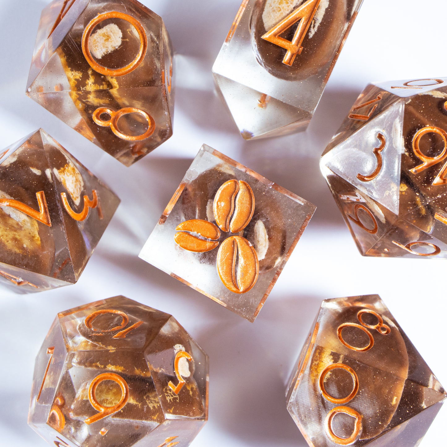 A bird’s-eye view of seven coffee themed dice, encircling an illustrated six-sided die in the center.