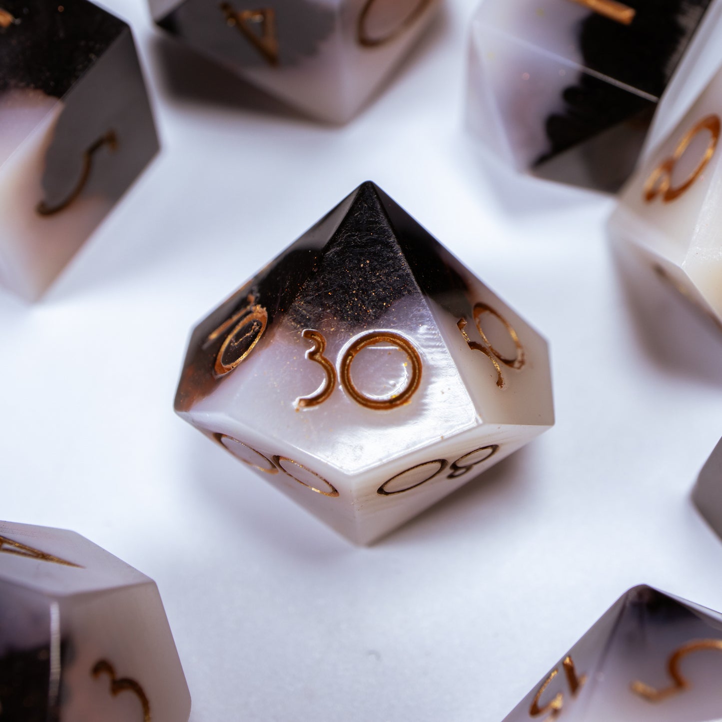 A close-up of a ten sided die at the heart of its kin, the rest of the coffee themed set arranged in a circle around it.
