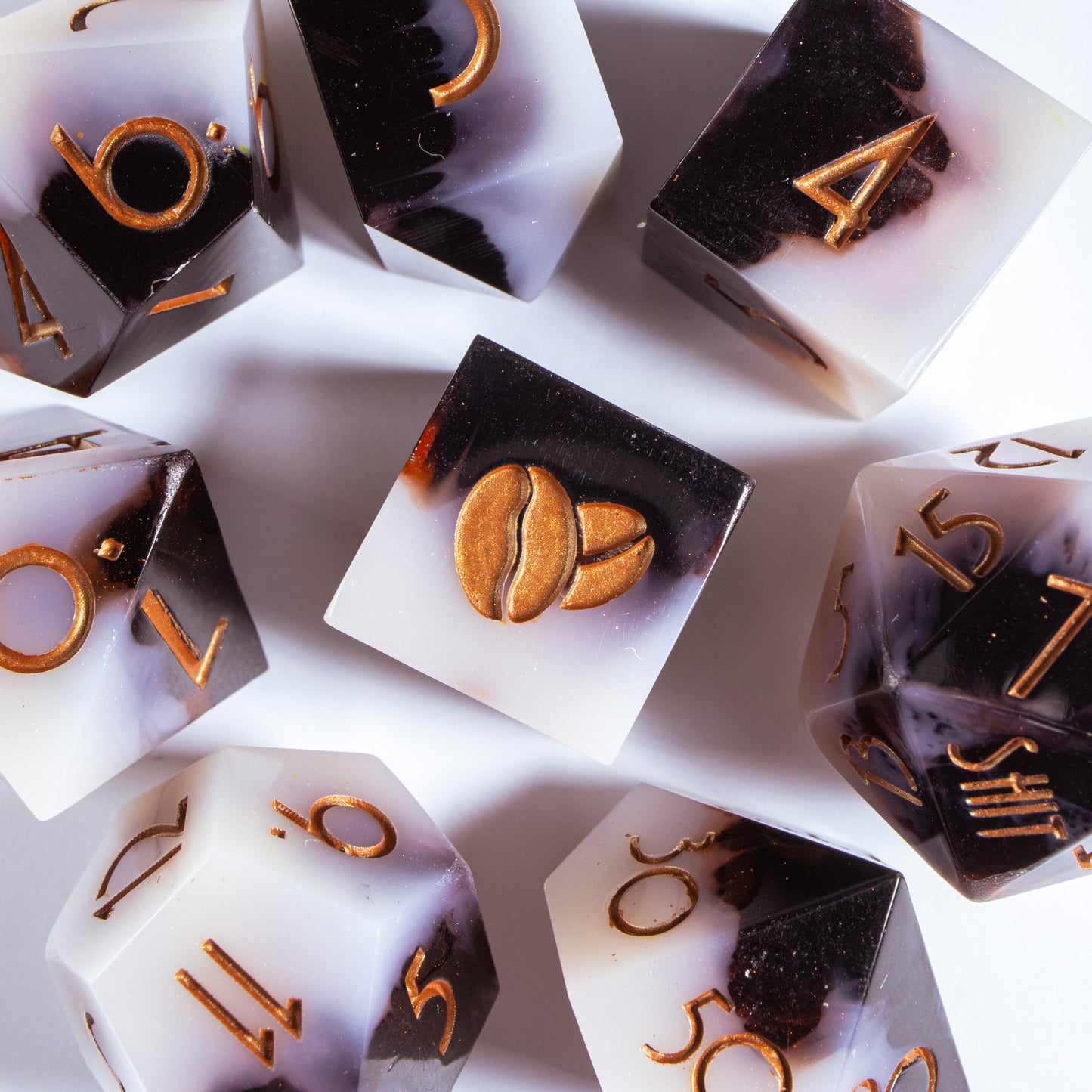 A bird’s-eye view of seven coffee themed dice, encircling an illustrated six-sided die in the center.