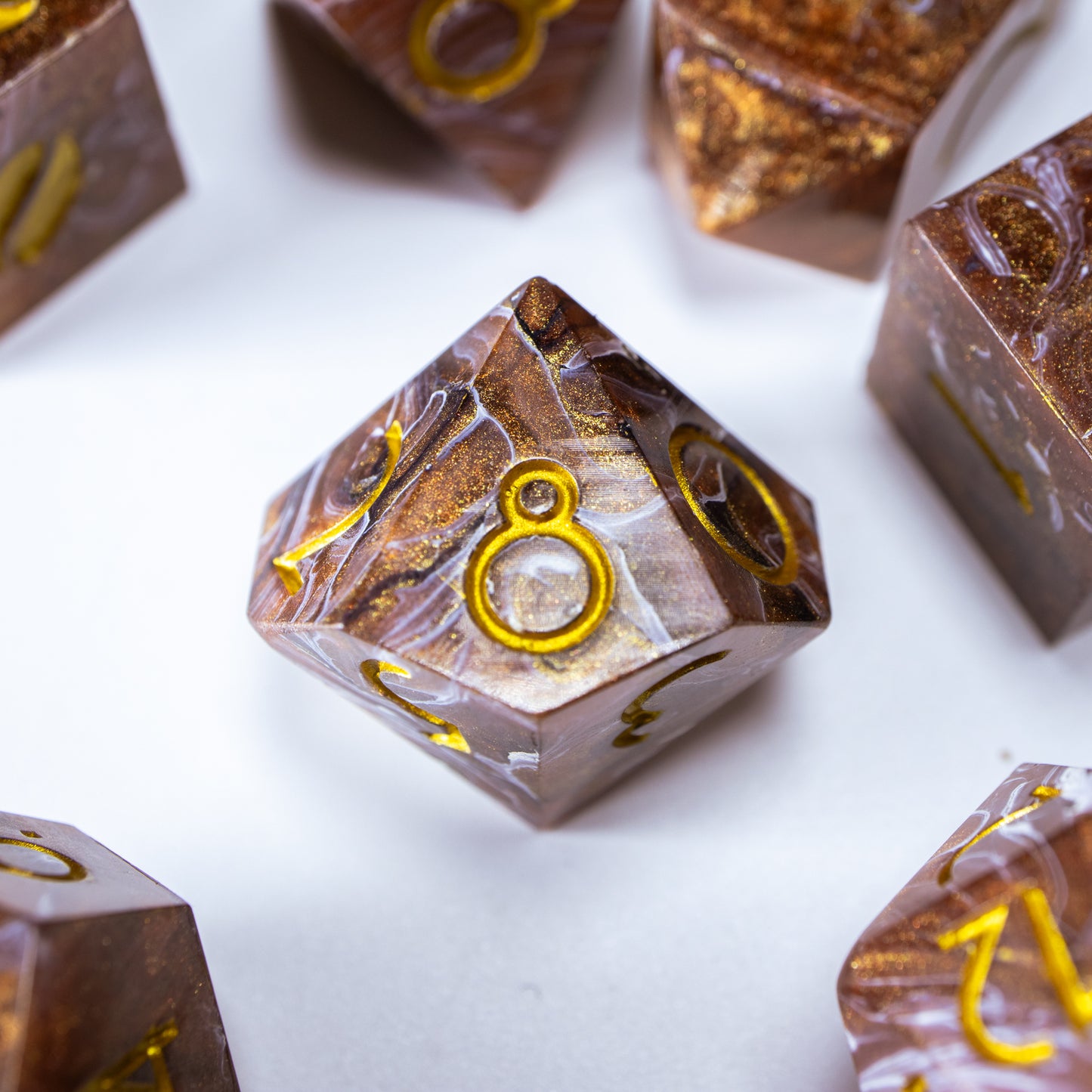 A close-up of a ten sided die at the heart of its kin, the rest of the coffee themed set arranged in a circle around it.
