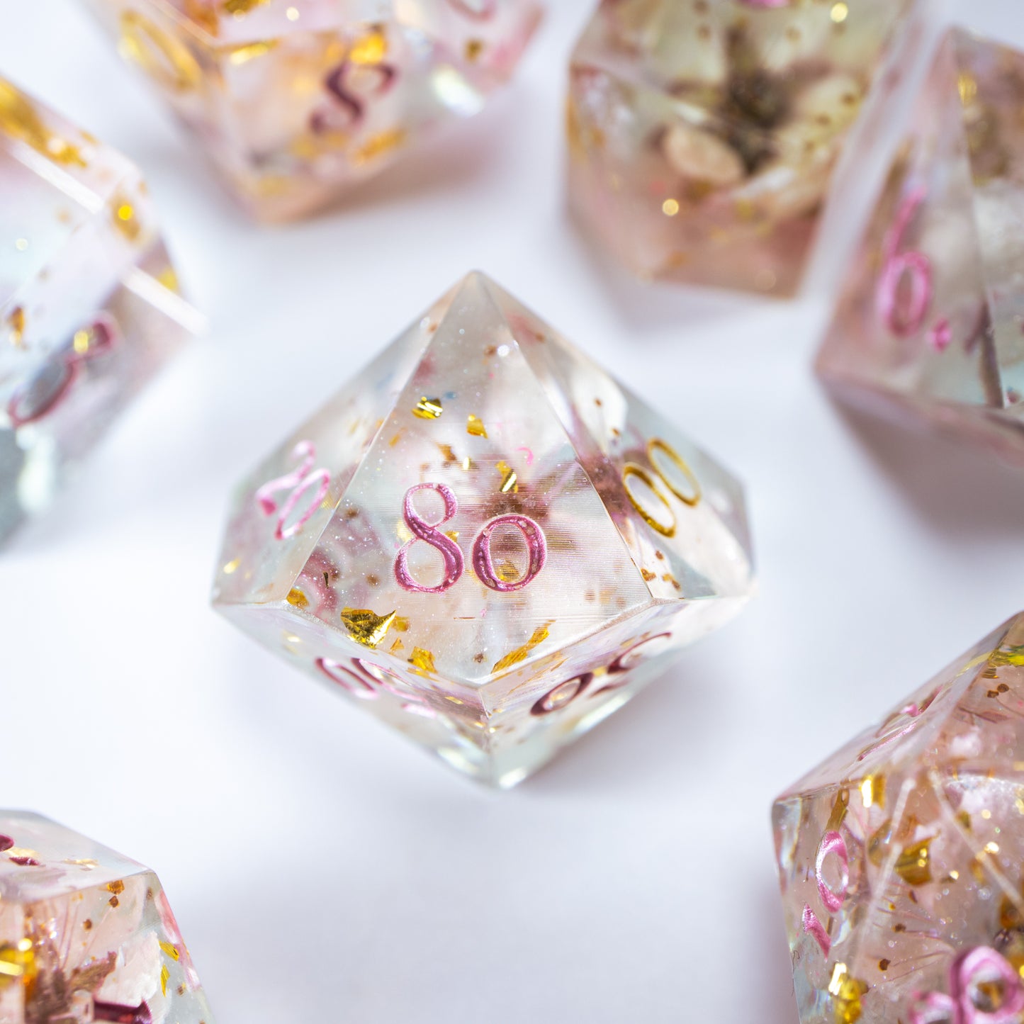 A close-up of a ten sided die at the heart of its kin, the rest of the dice set arranged in a circle around it.