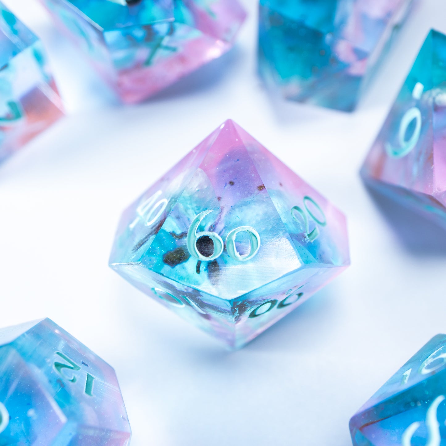 A close-up of a ten sided die at the heart of its kin, the rest of the dice set arranged in a circle around it.