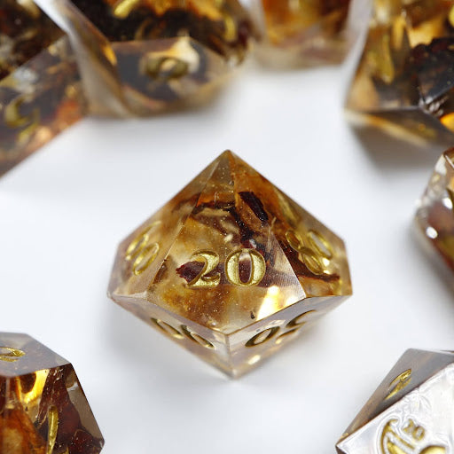 A close-up of a ten sided die at the heart of its kin, the rest of the tea themed set arranged in a circle around it.