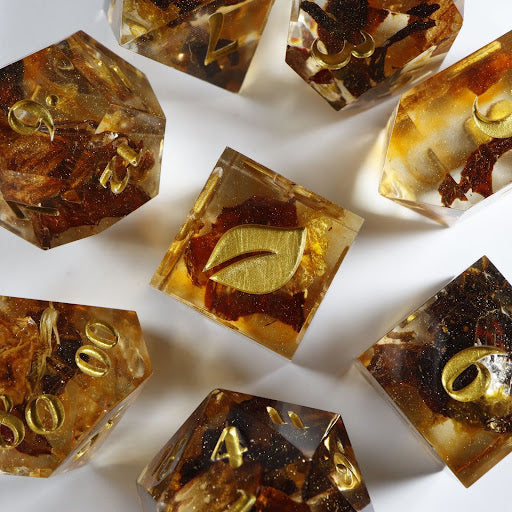 A bird’s-eye view of seven tea themed dice, encircling an illustrated six-sided die in the center.