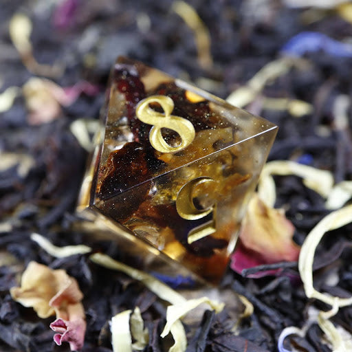 An eight-sided die, nestled gently on a pile of decorative tea leaves.