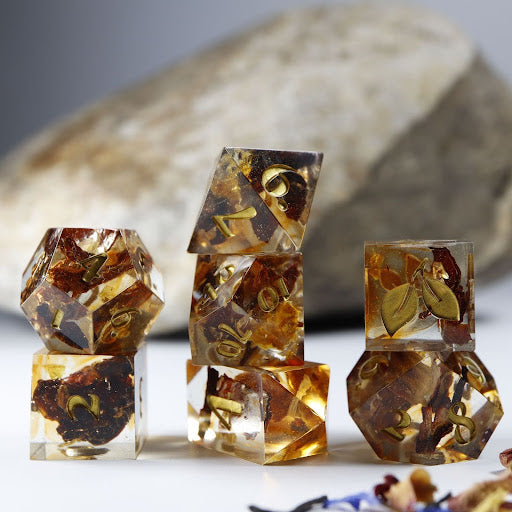 Three towers of stacked coffee themed dice with added background elements, such as an out of focus rock for added texture and decorative tea leaves.