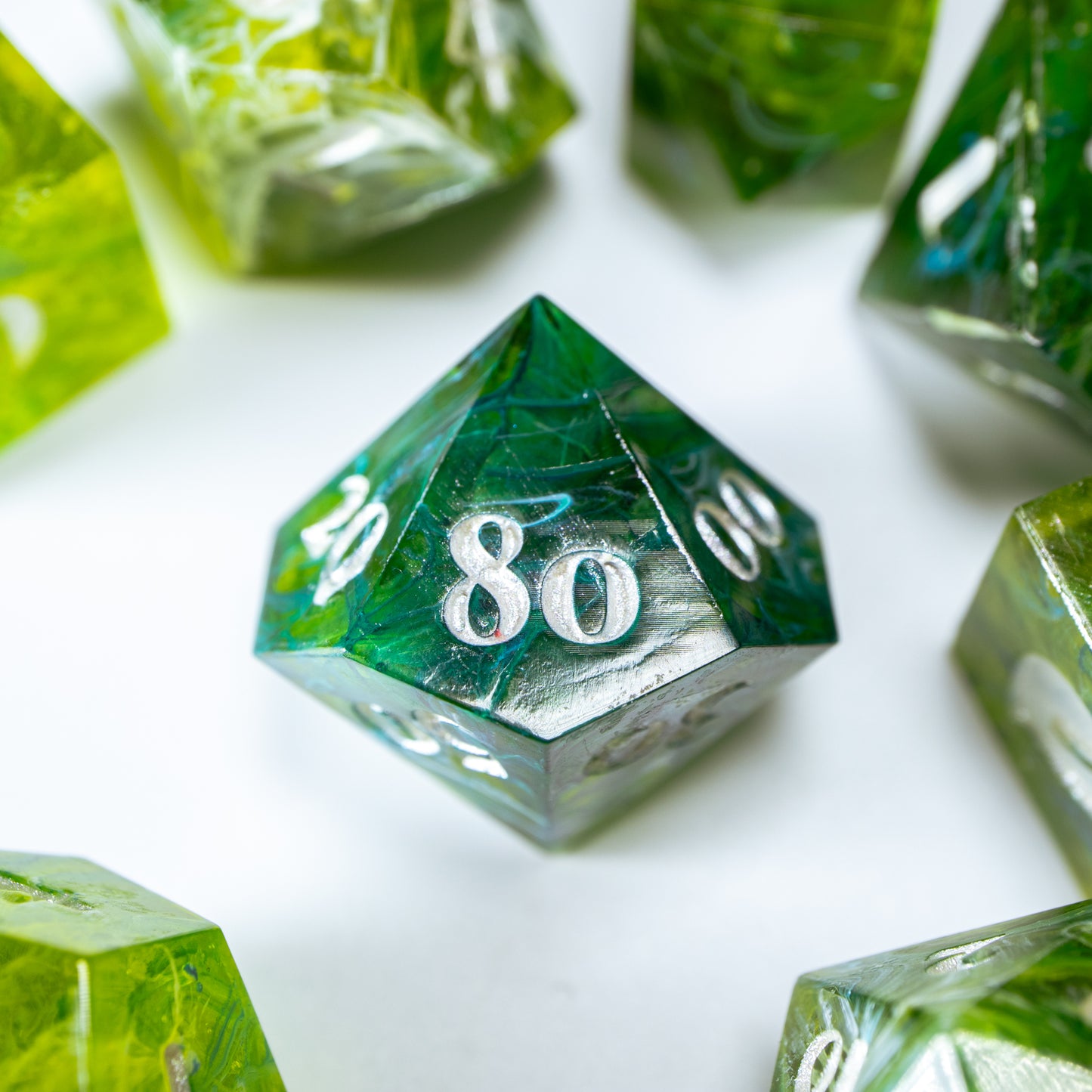 A close-up of a ten sided die at the heart of its kin, the rest of the tea themed set arranged in a circle around it.