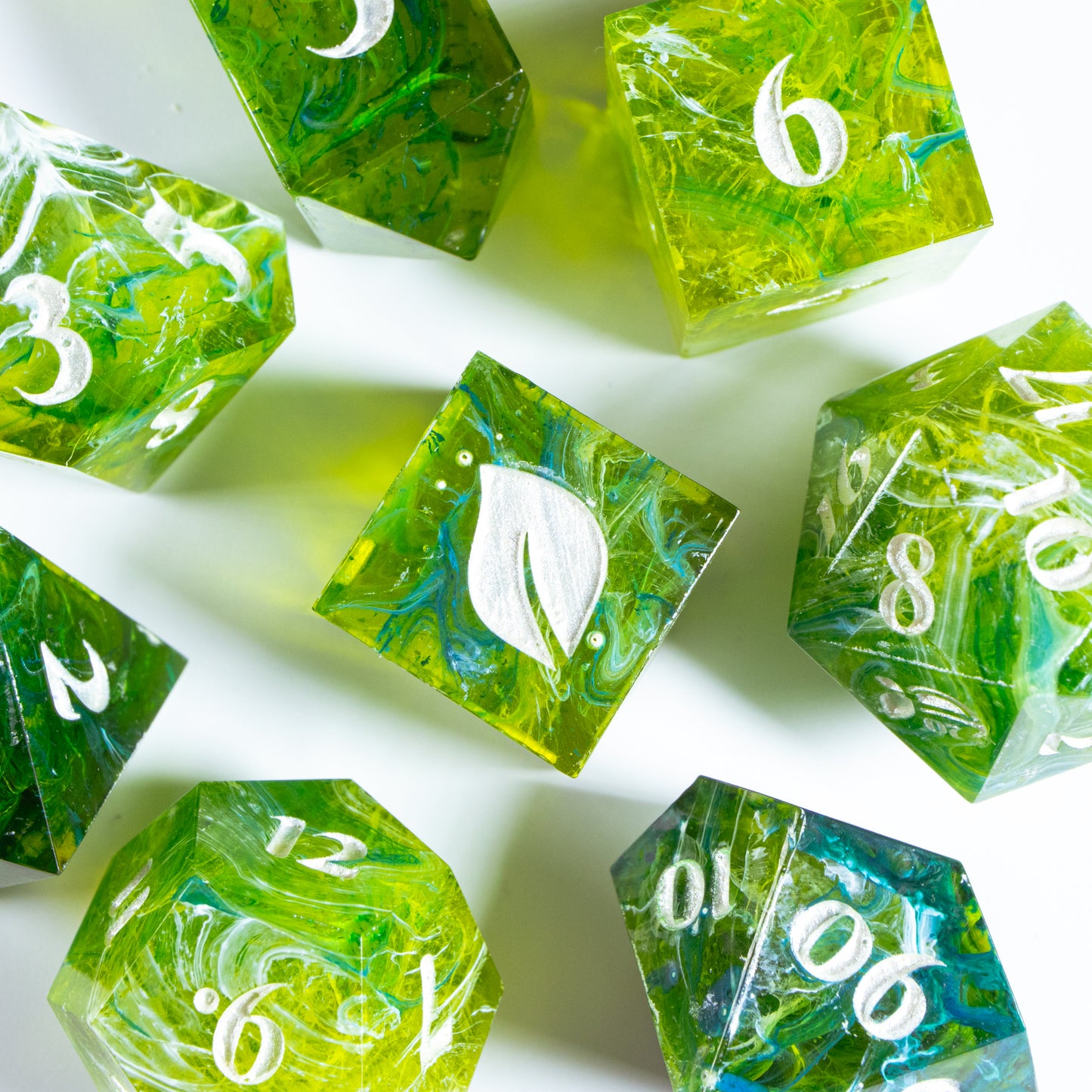 A bird’s-eye view of seven tea themed dice, encircling an illustrated six-sided die in the center.