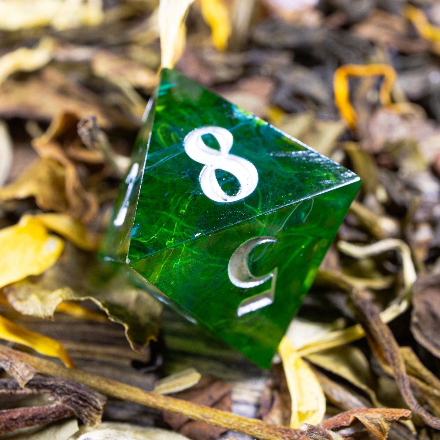 An eight-sided die, nestled gently on a pile of decorative tea leaves.