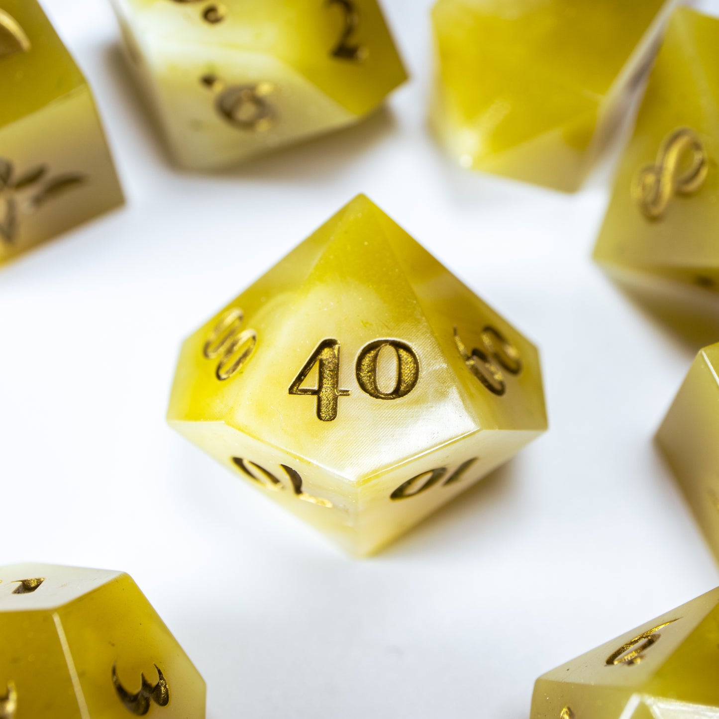 A close-up of a ten sided die at the heart of its kin, the rest of the tea themed set arranged in a circle around it.